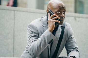 Lean Management - Thoughtful black entrepreneur speaking on cellphone and looking away